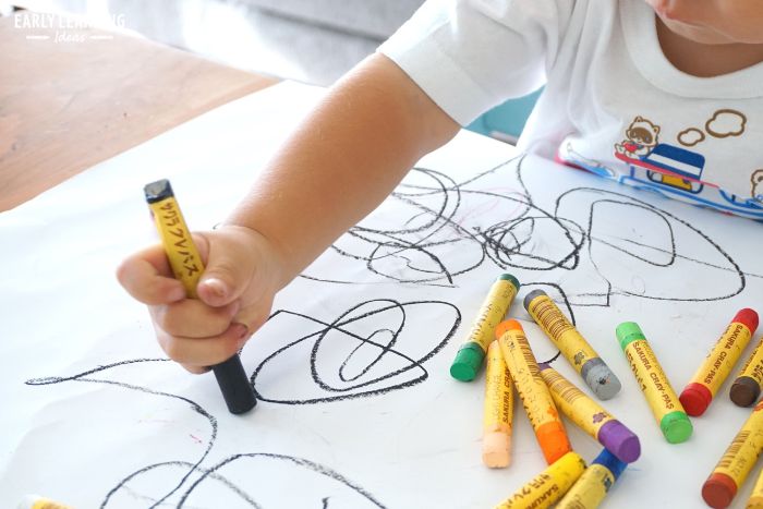 A young child using the Palmar supinate grip to draw shapes with a crayon. 