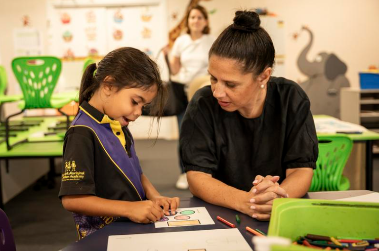 A teacher assisting a young student with a coloring activity